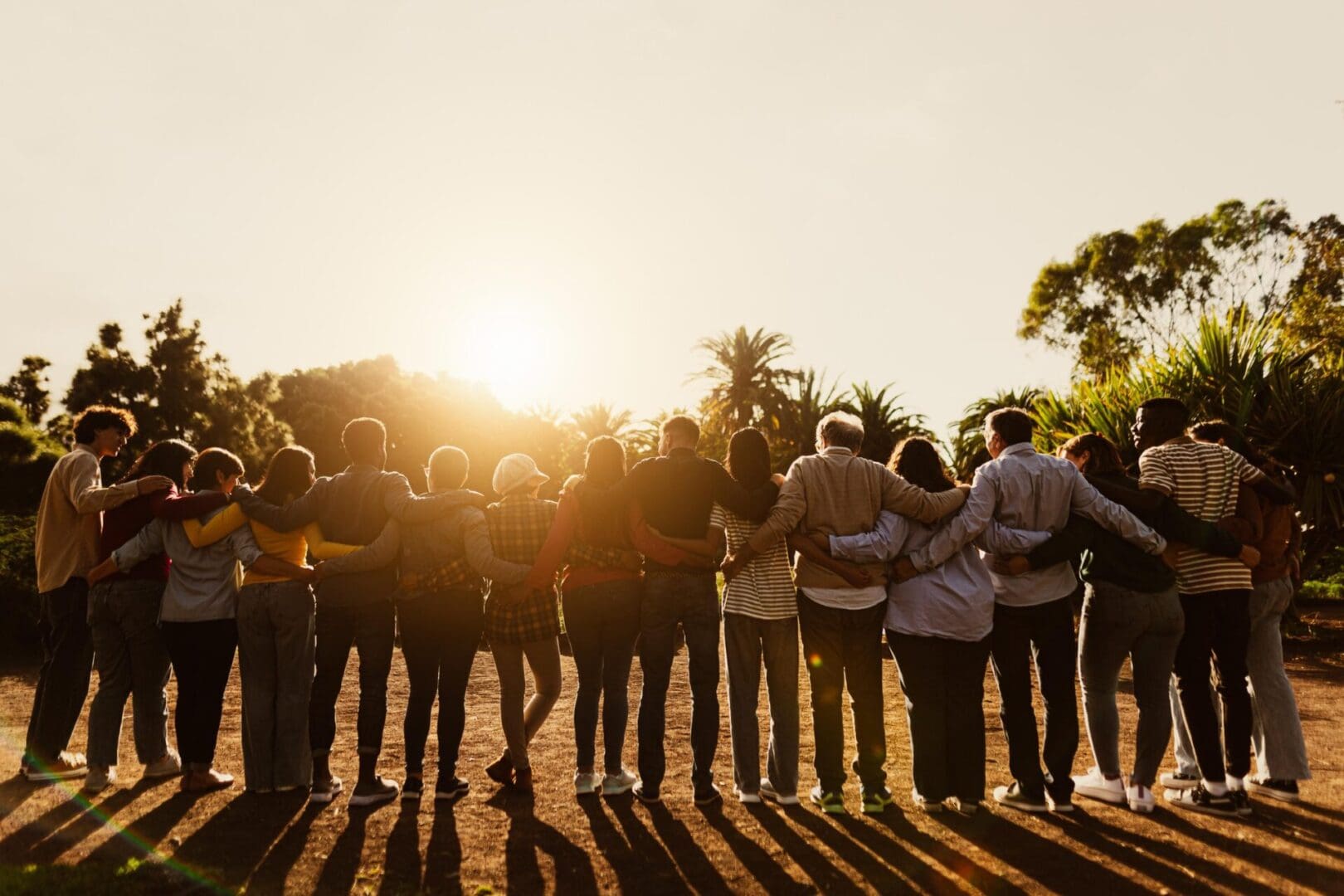 Group of people hugging at sunset.