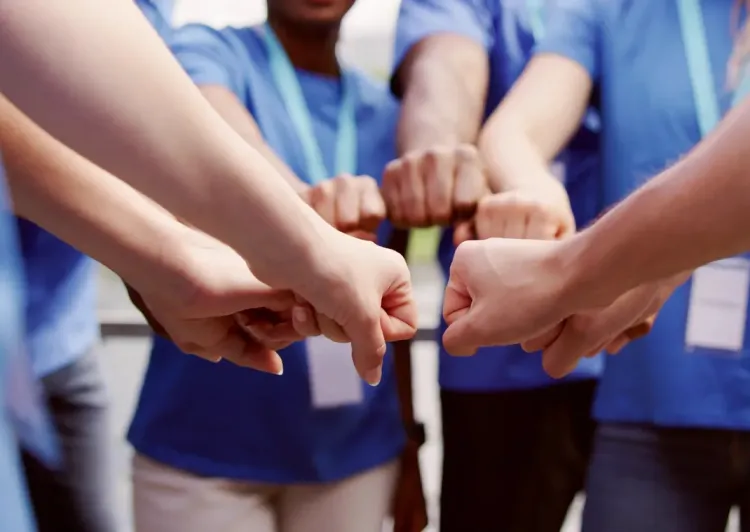 Group of people fist bumping together.