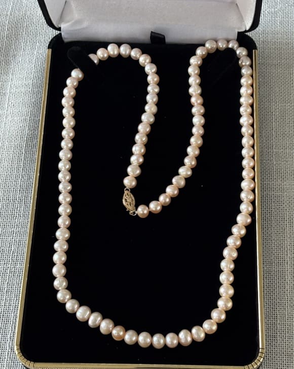 Pearl necklace displayed in elegant box.