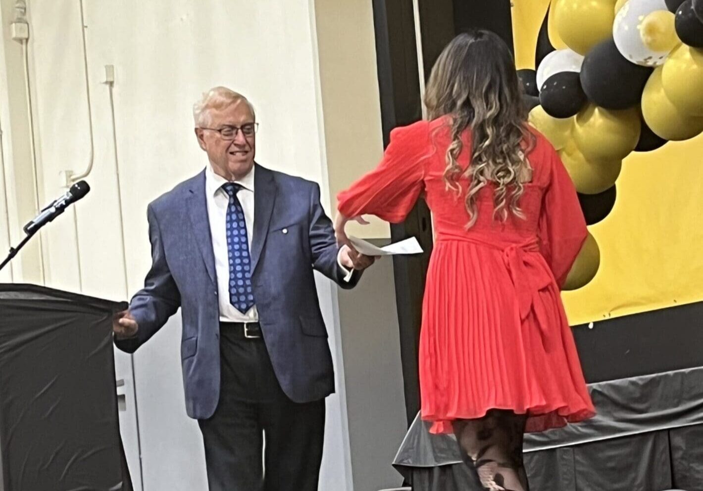 Man in suit handing diploma to woman.